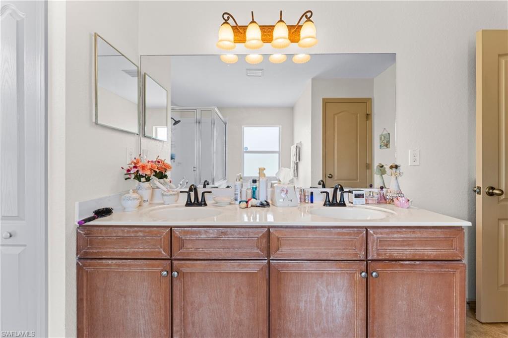 Dual sink vanity featuring wood-finish cabinetry, a neutral countertop, and a large wall-mounted mirror