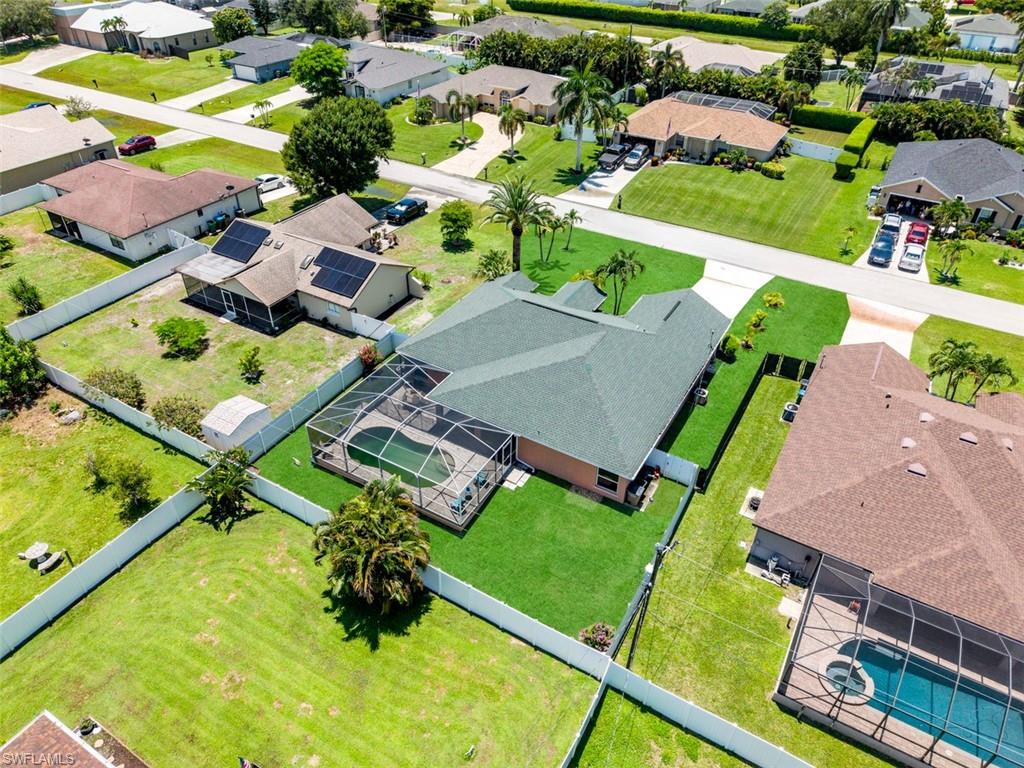 Property featuring a screened-in pool, mature landscaping, and a manicured lawn