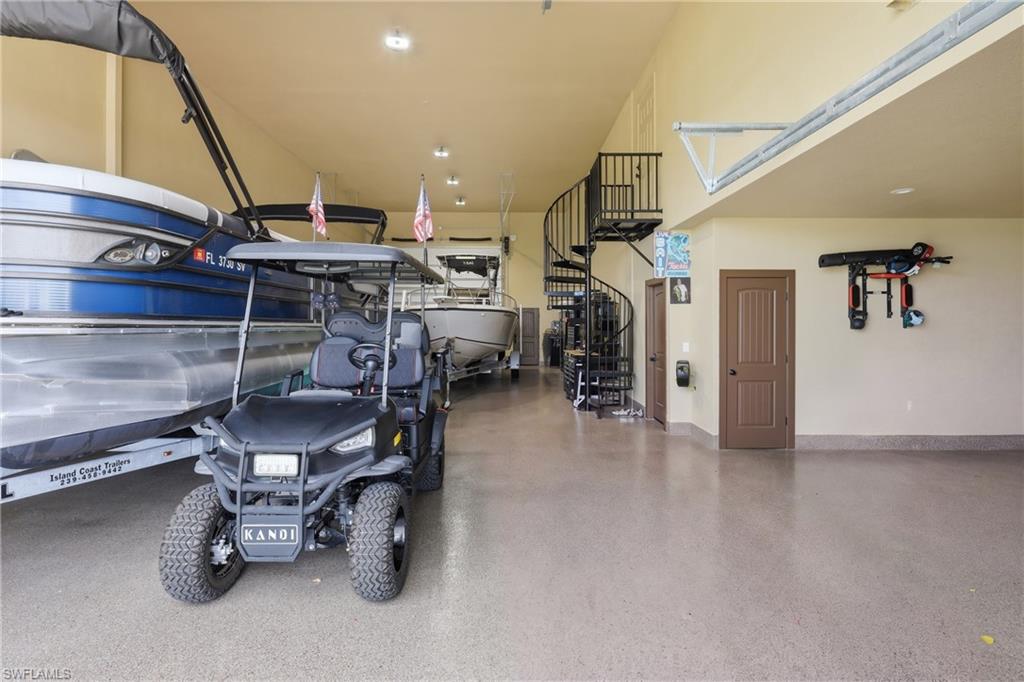 Massive/Expansive garage with high ceilings, epoxy flooring, a black spiral staircase, and multiple brown panel doors