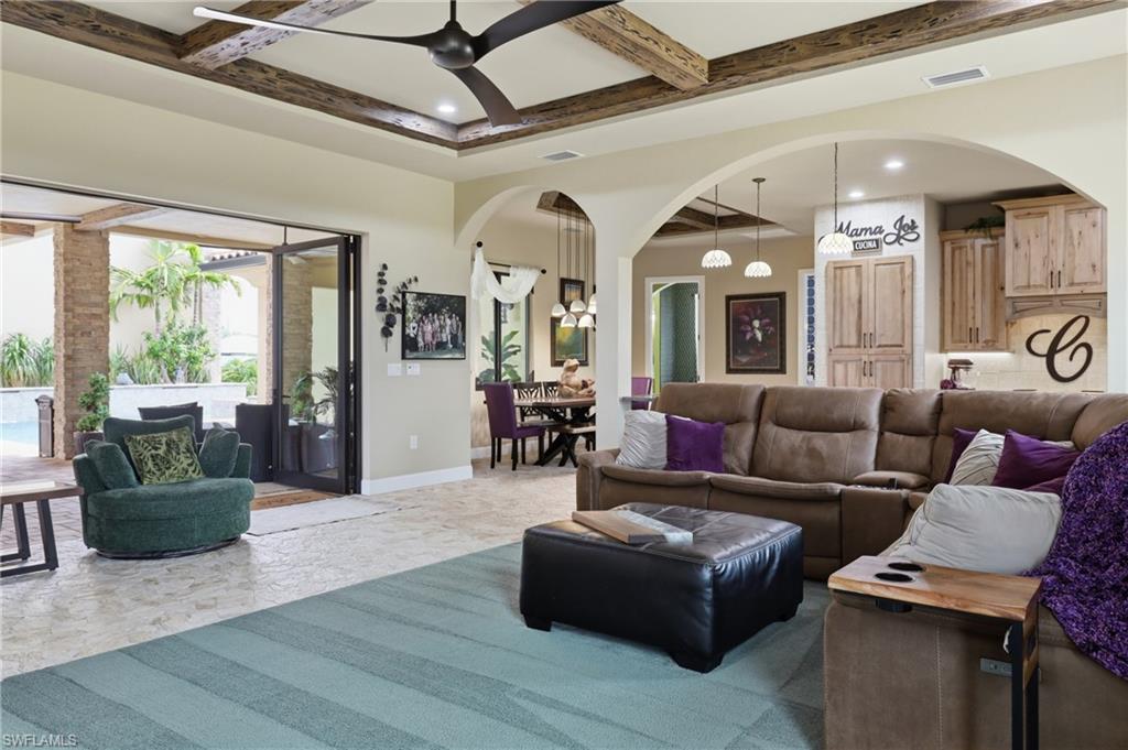Expansive living area with wood-beam tray ceilings and recessed lighting
