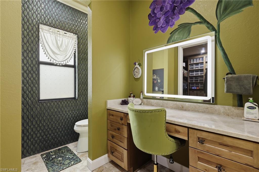 Vanity area featuring an illuminated mirror, wood-finish cabinetry, and a stone-finish countertop