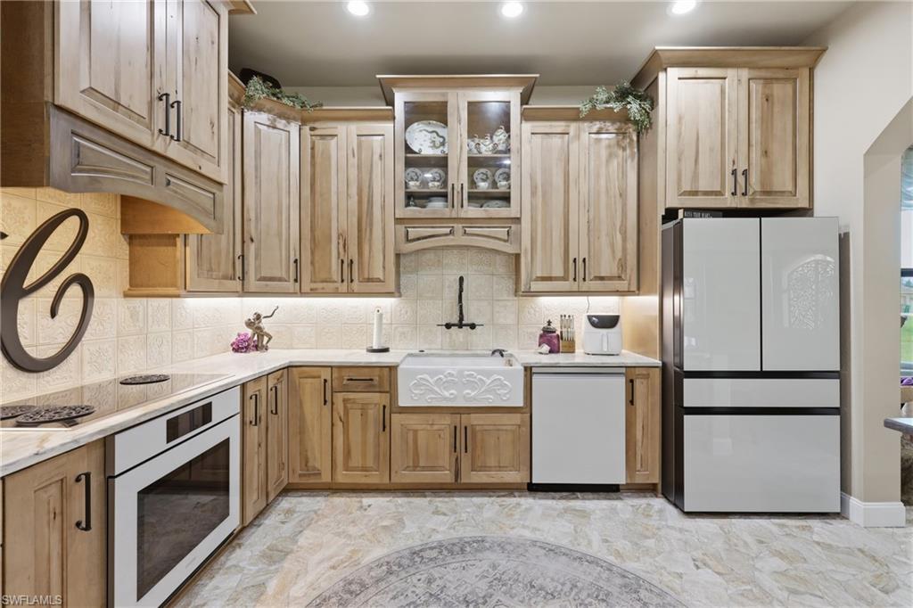 Modern kitchen featuring wood cabinetry, white countertops, textured tile backsplash, and a decorative farmhouse sink