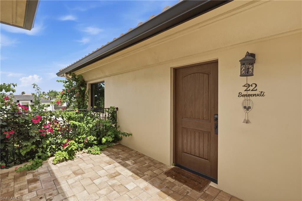 Exterior entryway of private apartment/guest suite featuring a wood-finish door, paver flooring, and an ornamental iron railing