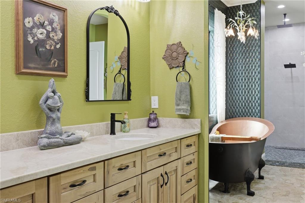 Double vanity with light wood-finish cabinetry, light-colored countertop, and a single basin sink with a matte black faucet