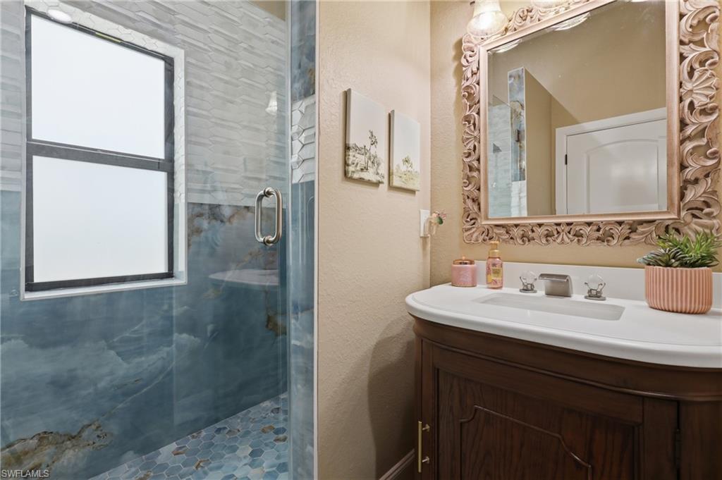 Shower enclosure featuring blue-toned stone-look wall tiling and blue hexagon floor tiles