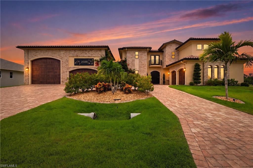 Stately exterior featuring a paver driveway, stone accents, arched garage doors,
