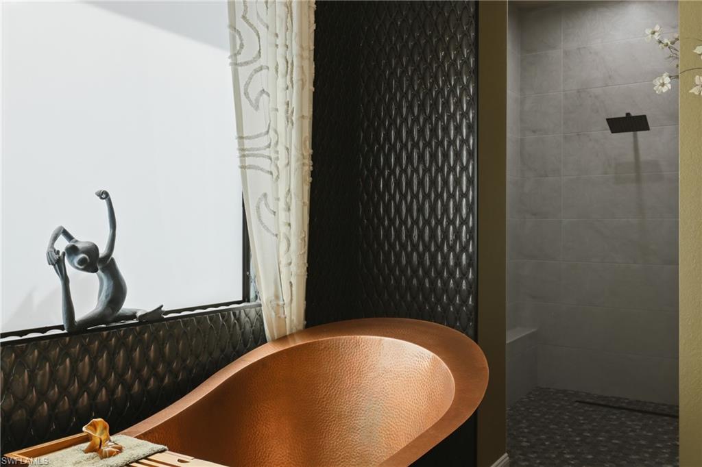 Freestanding copper soaking tub with textured wall tiling