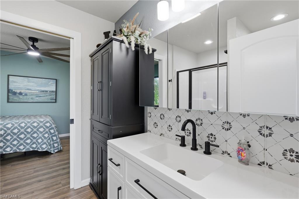 Modern bathroom vanity featuring a white integrated sink, matte black faucet, and patterned tile backsplash