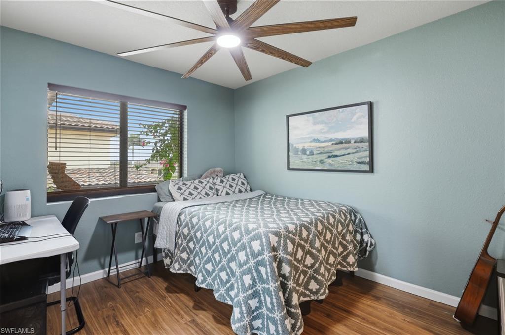 Room featuring wood-finish flooring, a ceiling fan with integrated lighting, and a window with blinds