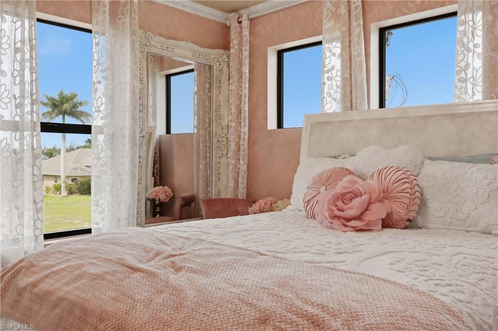 Room featuring multiple windows with natural light, a decorative mirror with an ornate frame, a light-colored headboard, and textured wall finish