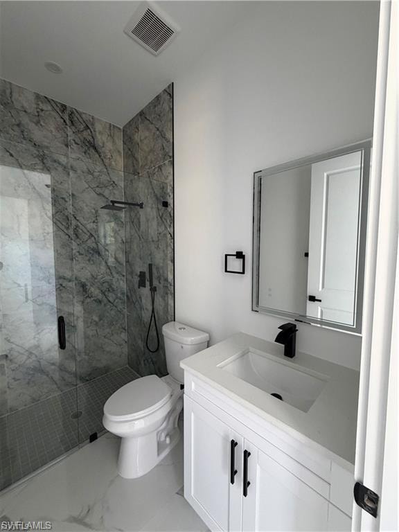 Modern bathroom featuring a walk-in shower with clear glass enclosure and gray marble-patterned tile, white vanity with integrated sink and matte black faucet, and white tile flooring
