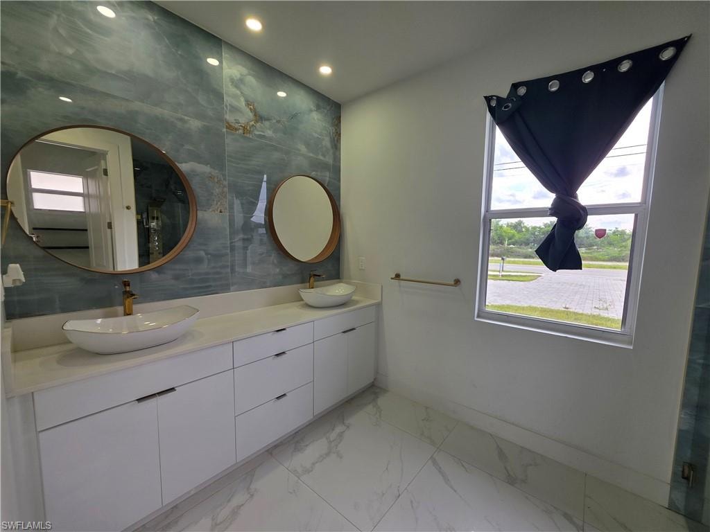 Bathroom featuring a double vanity with vessel sinks, white cabinetry, and a light-colored countertop