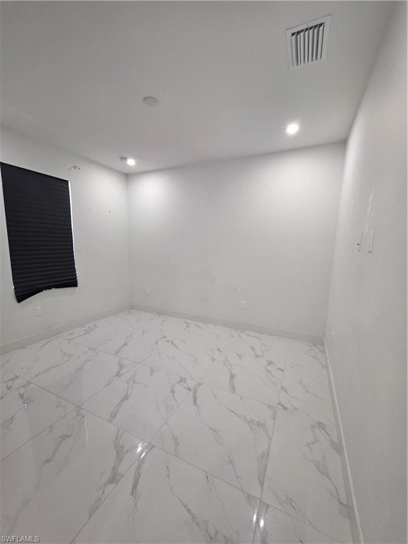 Spacious room featuring large format tile flooring with a marble-effect finish, recessed ceiling lighting, a dark privacy blind, and a ceiling-mounted air vent