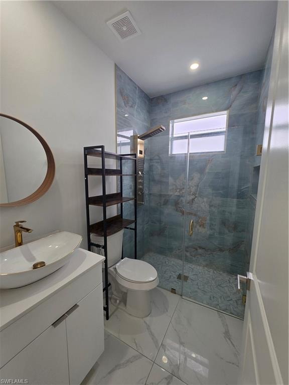 Bathroom featuring a vessel sink with a gold-tone faucet, a glass-enclosed shower with a multi-function shower panel, and large format marble-look floor tiles