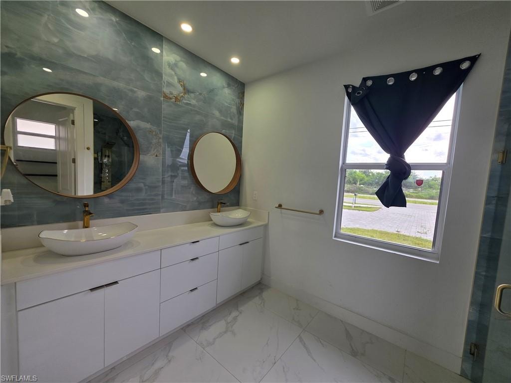 Dual vessel sinks with gold-tone fixtures and a large vanity featuring white cabinetry
