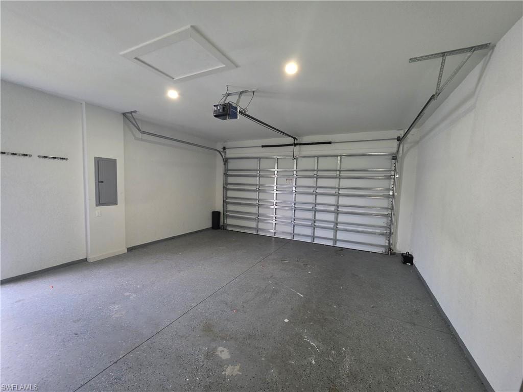Spacious garage featuring a durable epoxy-coated concrete floor, an automatic overhead door opener, recessed lighting, and a clearly visible electrical panel