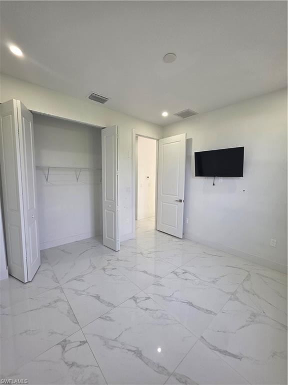 Spacious room featuring large format tile flooring, recessed lighting, white bifold closet doors, and a solid core interior door