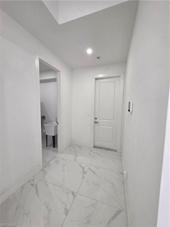 Hallway featuring large format marble-look tile flooring, white interior doors, and recessed lighting