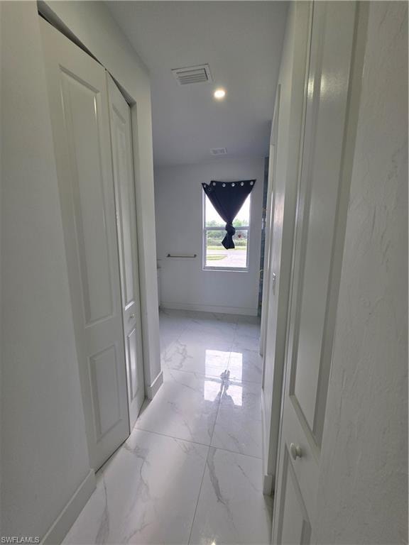 Hallway featuring white panel doors, recessed lighting, white tile flooring, and a window providing natural light
