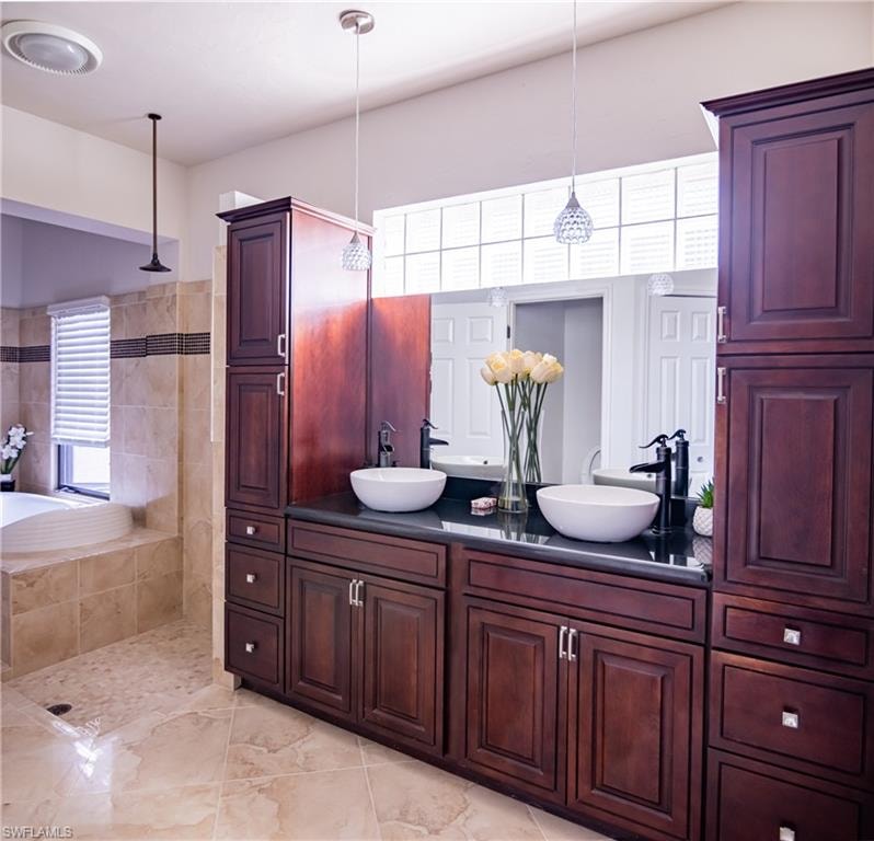 Dual vessel sinks with wall-mounted black faucets, dark wood cabinetry, and a full-width vanity mirror