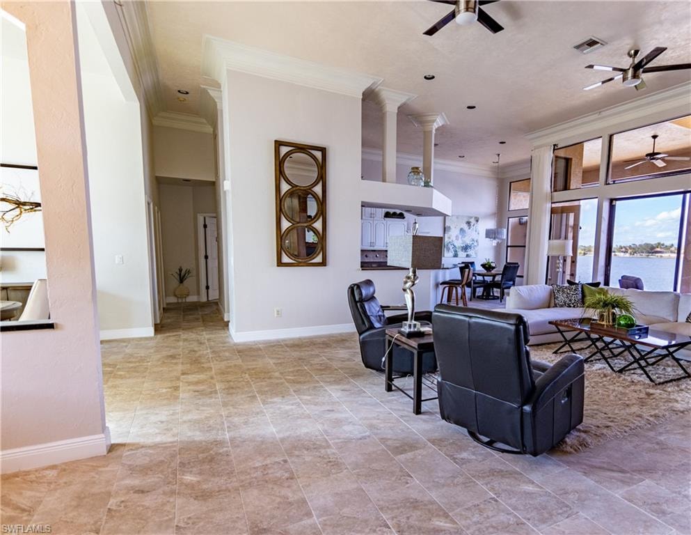 Open-concept living area featuring large format tile flooring, crown molding, and extensive window views of the waterway
