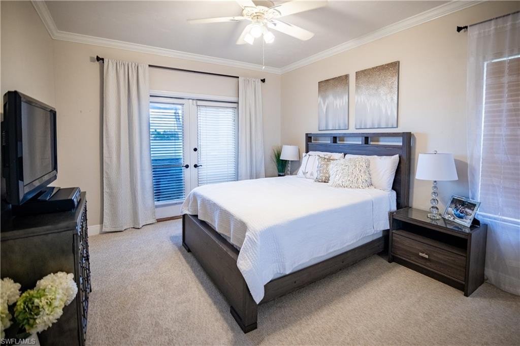 Carpeted room featuring a ceiling fan, crown molding, and double French doors with blinds