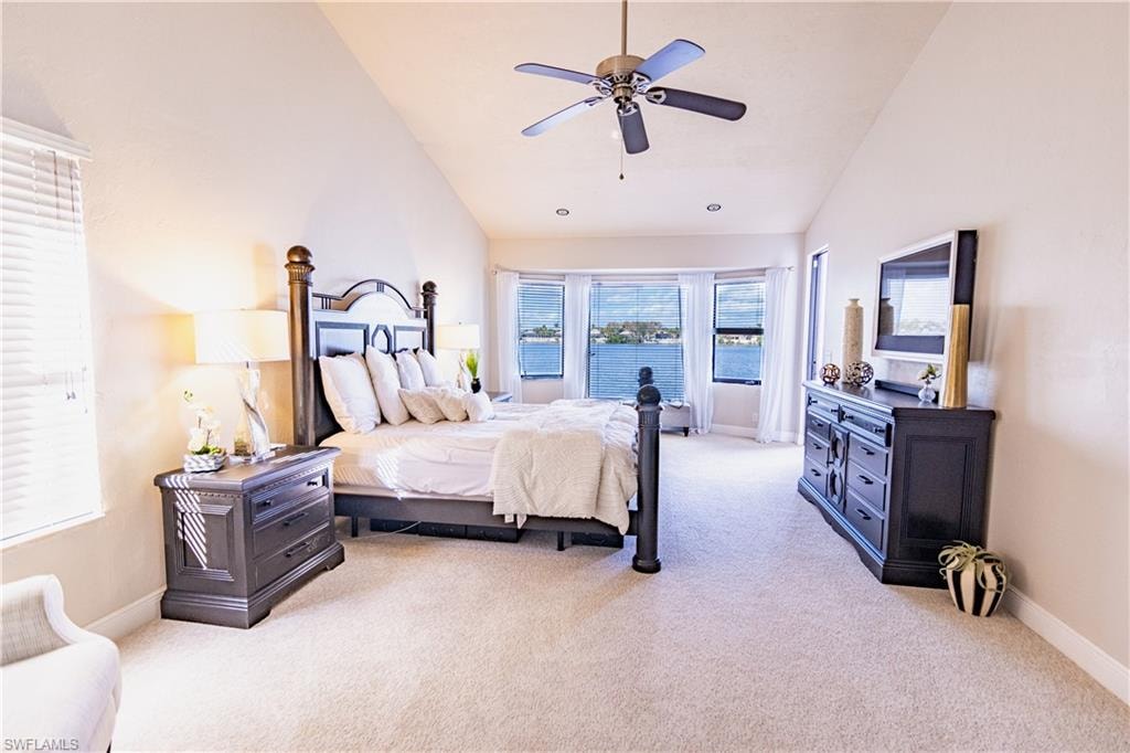 Vaulted ceiling bedroom with waterfront windows, recessed lighting, and a ceiling fan