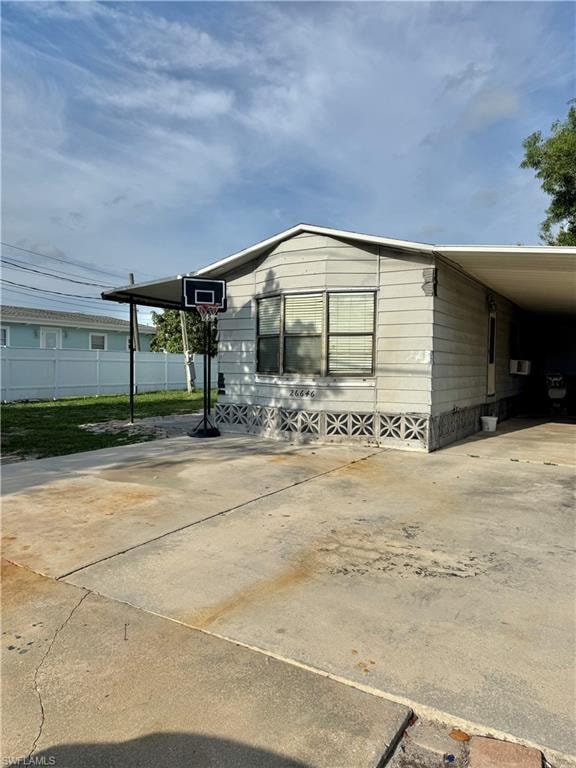 Exterior featuring light-colored siding, a covered carport, and a concrete driveway