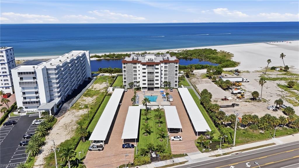 Coastal high-rise community with ocean proximity, covered parking structures, a central swimming pool, and landscaped grounds - Virtually Edited Image