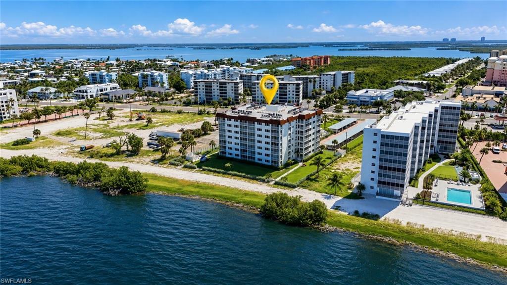 Modern multi-story residential building featuring clean architectural lines, expansive landscaped grounds with mature palm trees, and manicured lawn perimeter - Virtually Edited Image