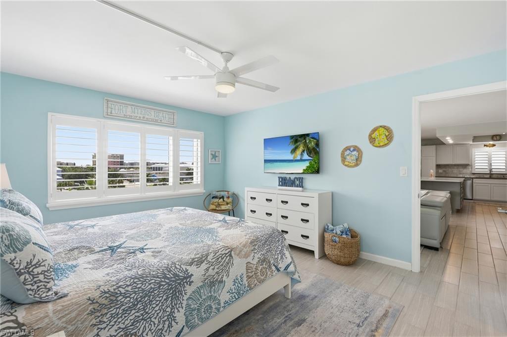 Window with white plantation shutters, white ceiling fan, and light wood-finish flooring - Virtually Edited Image