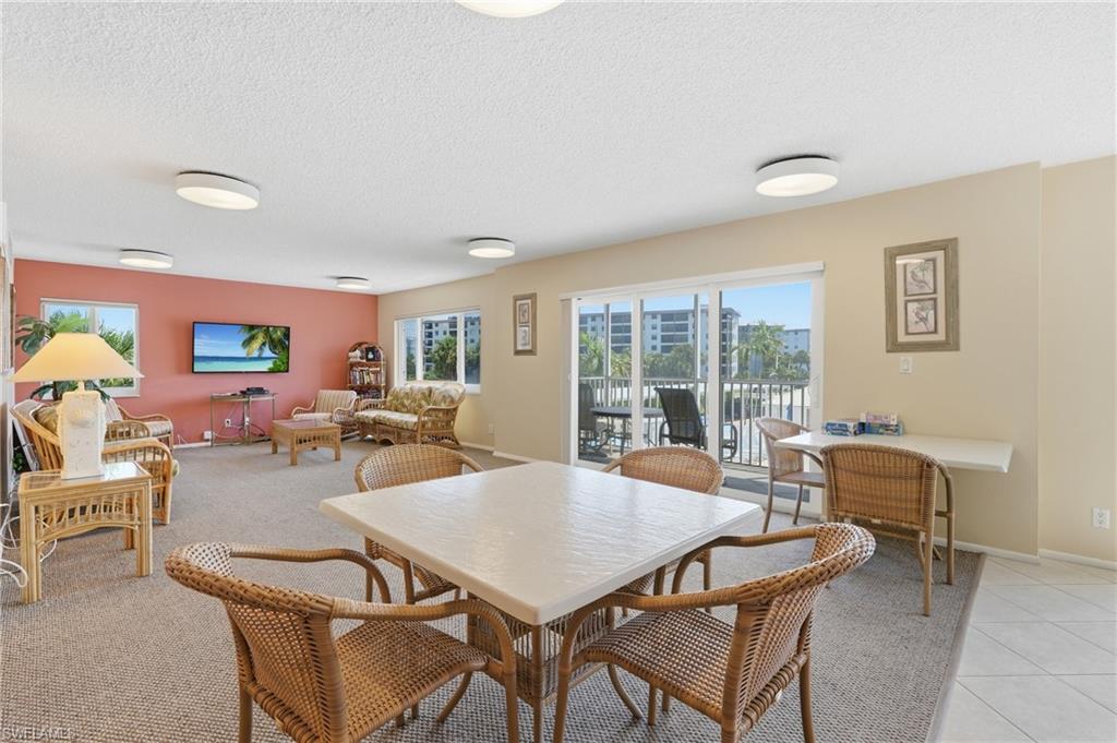 Spacious open-concept living area with recessed ceiling lighting, large sliding glass doors opening to a private balcony, neutral wall finishes, and tile flooring - Virtually Edited Image