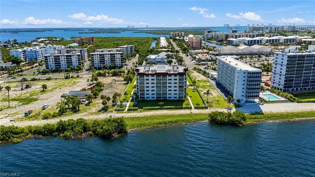 Modern multi-story residential building featuring clean architectural lines, expansive landscaped grounds with mature palm trees, and manicured lawn perimeter - Virtually Edited Image