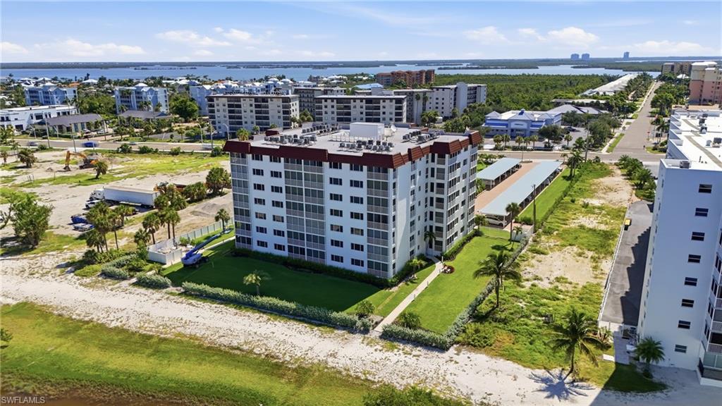 Modern multi-story residential building featuring clean architectural lines, expansive landscaped grounds with mature palm trees, and manicured lawn perimeter - Virtually Edited Image