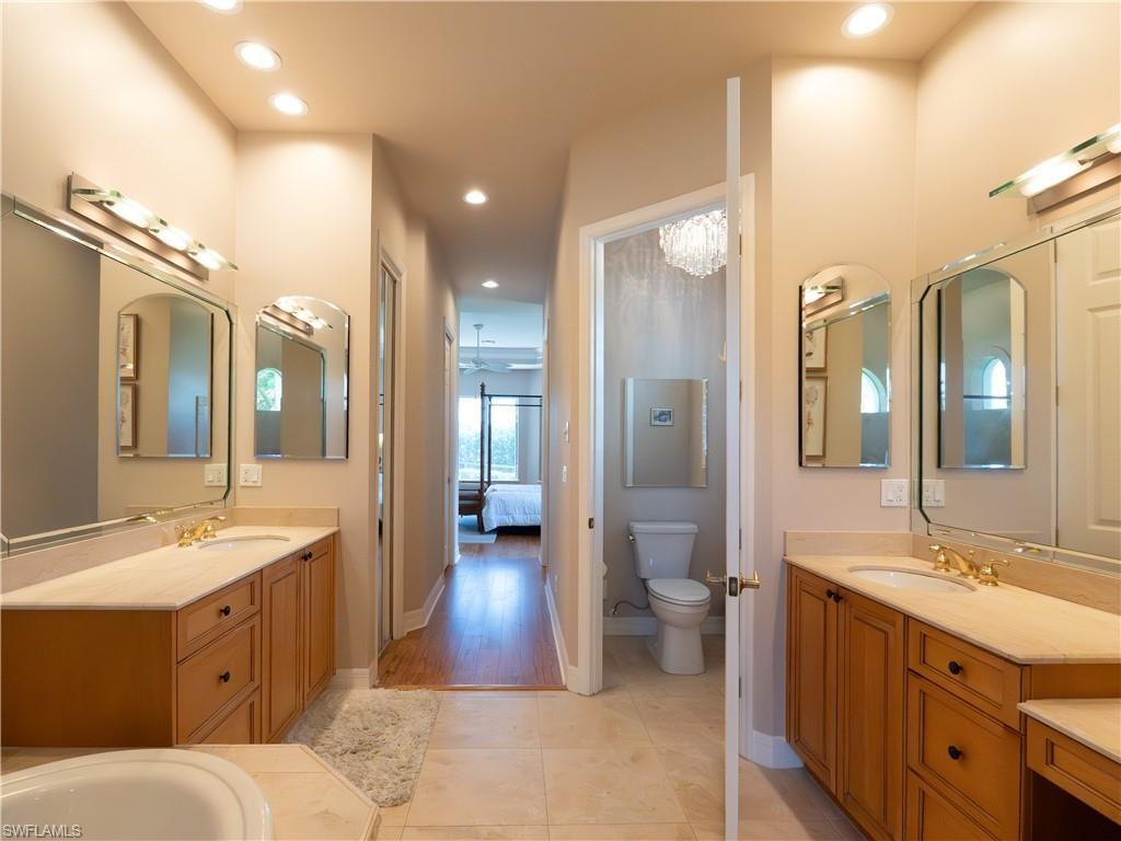 Dual vanity with wood-finish cabinetry, light-toned countertops, and framed mirrors