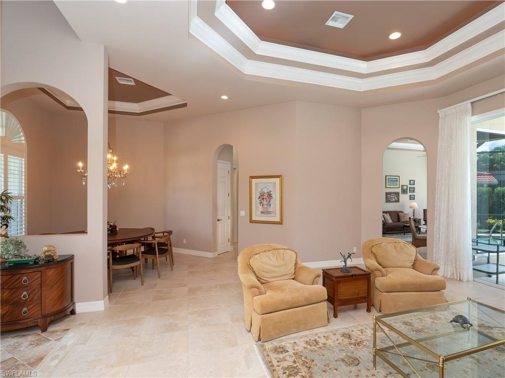 Tray ceilings with recessed lighting, arched doorways, tiled flooring, chandelier lighting, and plantation shutters