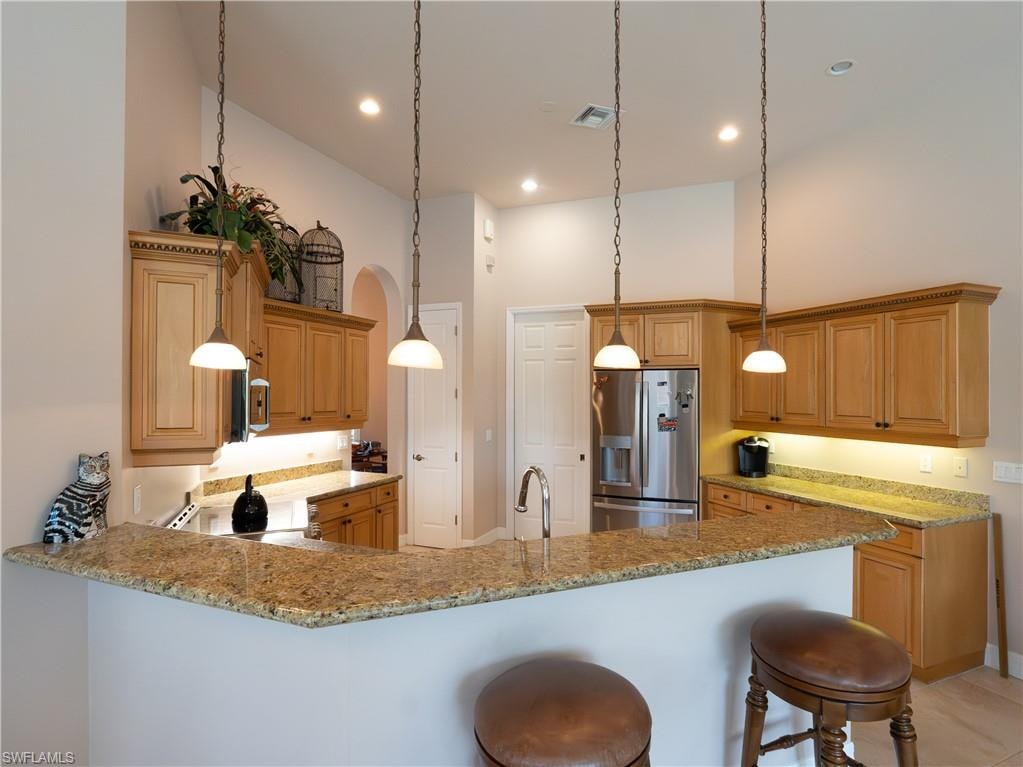 Expansive kitchen featuring light wood cabinetry, granite countertops, stainless steel appliances, and pendant lighting