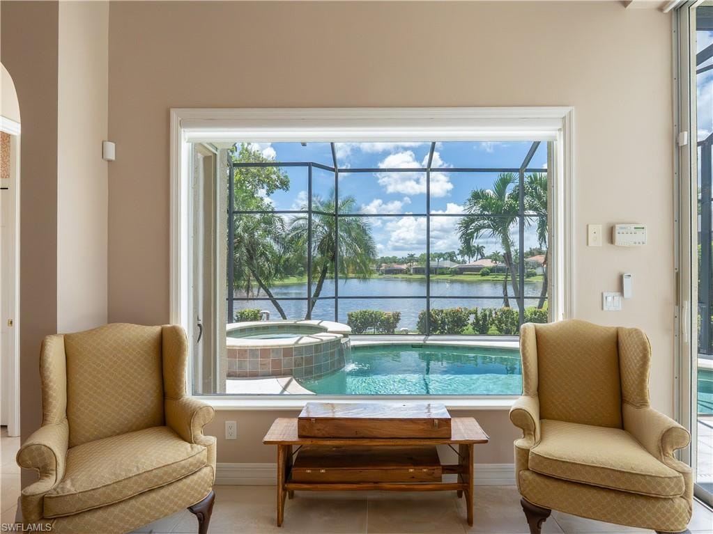 Expansive window overlooking a screened-in lanai with a pool and spa, and a serene water body beyond