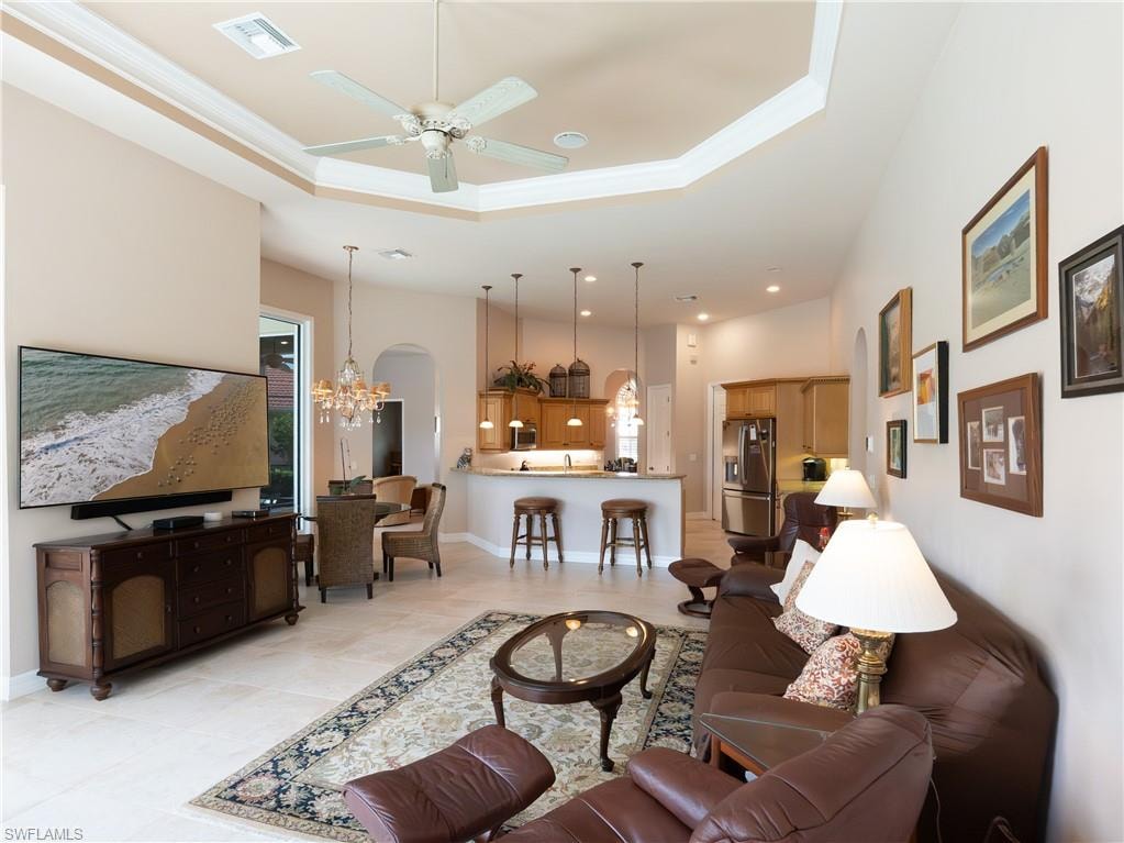 Tray ceiling with a ceiling fan, recessed lighting, tile flooring, and an archway entrance