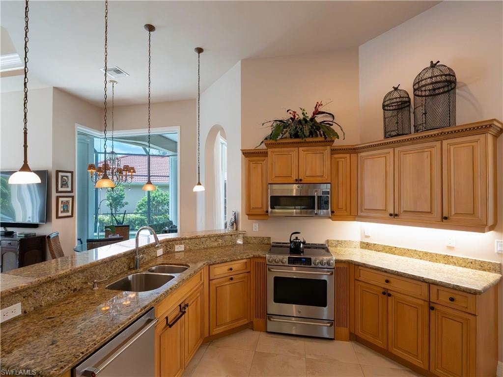 Kitchen featuring wood cabinetry, stainless steel appliances, and stone countertops