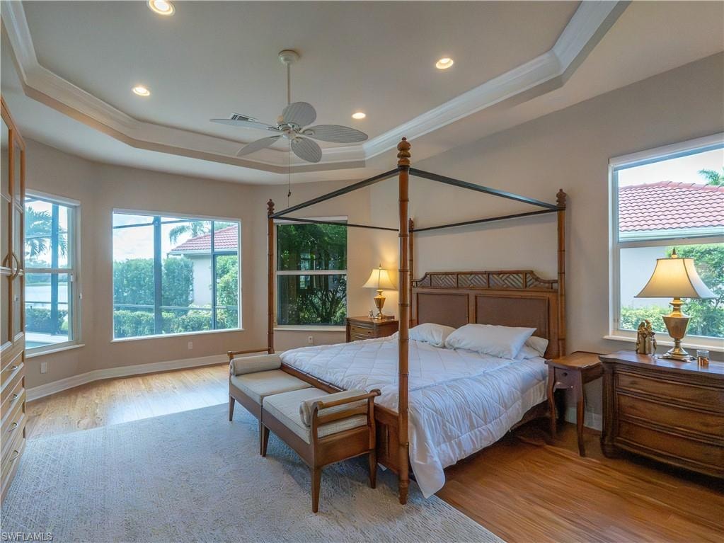 Tray ceiling with recessed lighting and a ceiling fan, wood-finish flooring, multiple windows, and built-in cabinetry