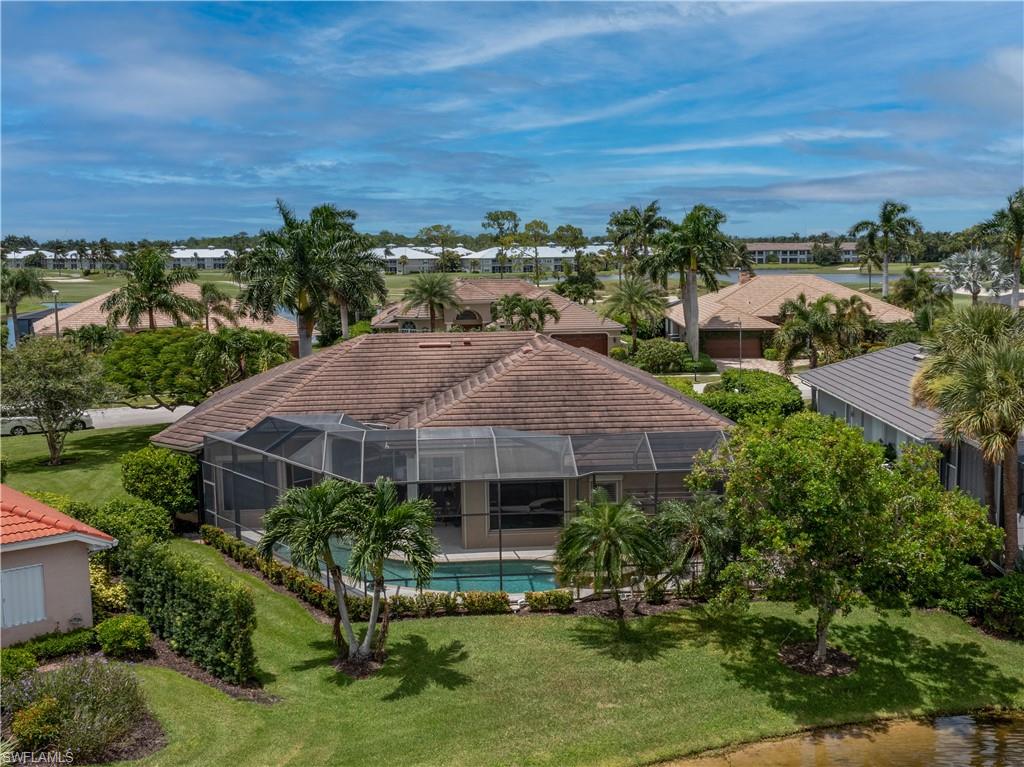 Screened-in pool area, tile roof, lush landscaping, and a water feature at the property's edge