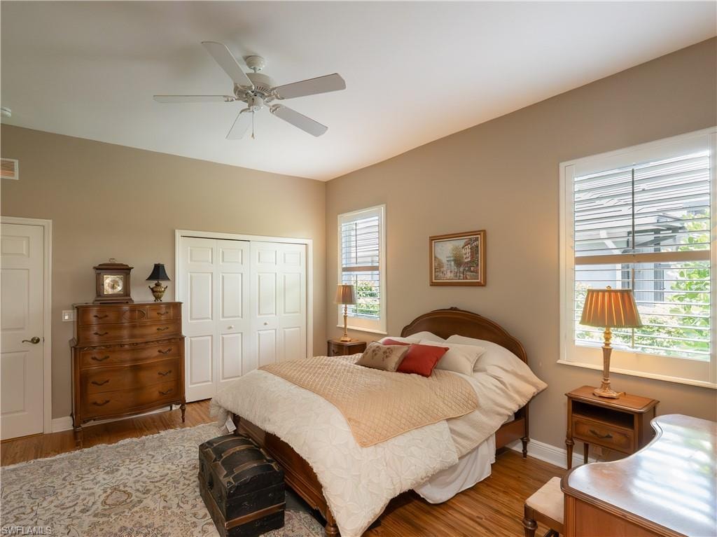 Hardwood flooring, two windows with plantation shutters, ceiling fan, and bi-fold closet doors