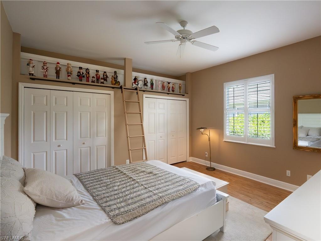 Sloped ceiling with ceiling fan, wood-finish flooring, plantation shutters, and built-in closet storage