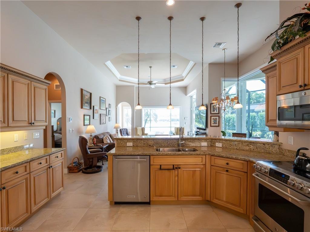 Kitchen featuring light wood cabinetry, stone countertops, stainless steel appliances, tile flooring, and pendant lighting