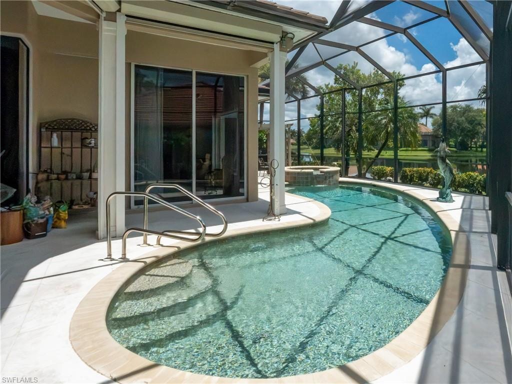 Screened pool enclosure featuring a custom-shaped pool, integrated spa, and spacious deck area