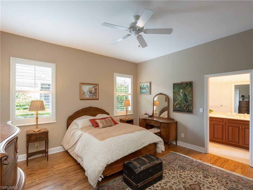 Vaulted ceiling with a ceiling fan, light wood-finish flooring, and multiple windows with plantation shutters