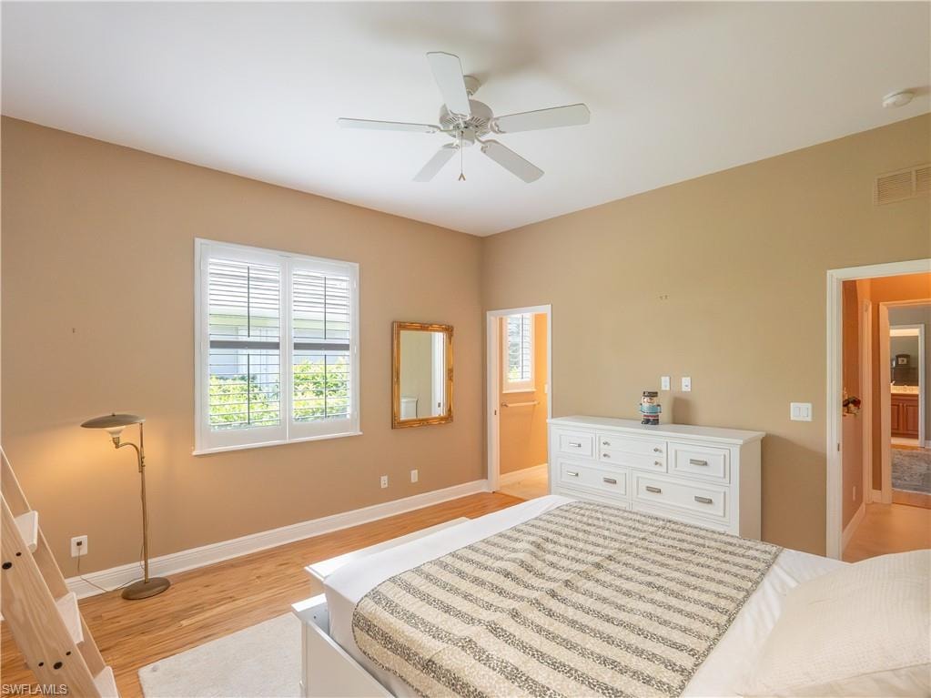 High ceilings, wood-finish flooring, white plantation shutters, and a ceiling fan
