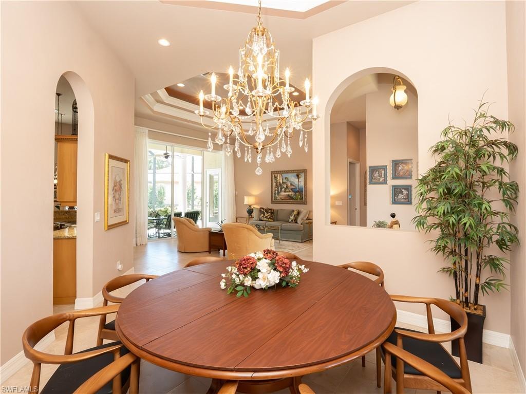 Arched doorways, coffered ceiling, crystal chandelier, tile flooring, and large glass doors