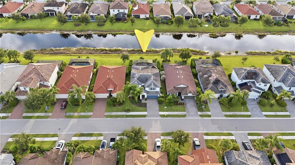 Waterfront residential community featuring a row of single-family homes with varied architectural styles, manicured lawns, mature landscaping, and direct water access